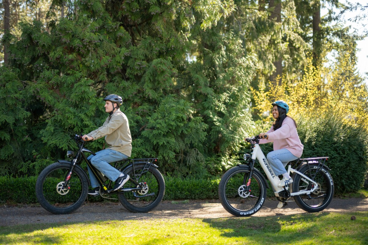 A couple rides bikes along a bike trail on a sunny day