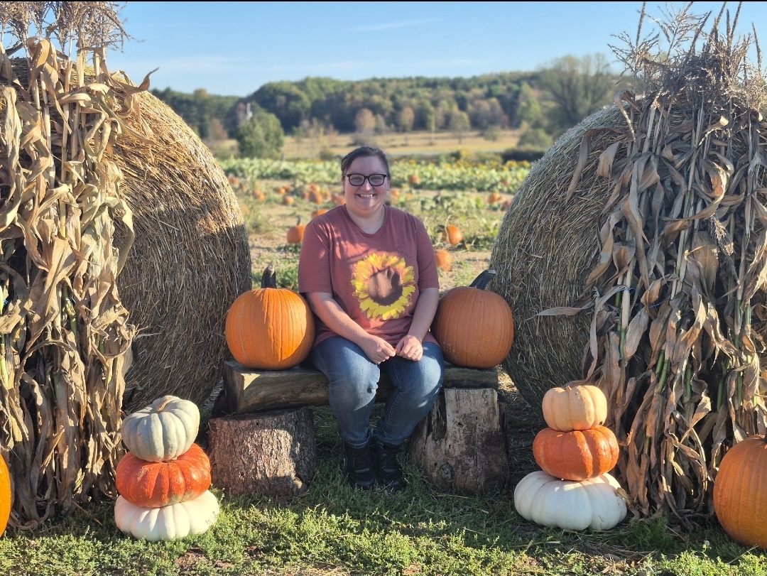 Woman sitting next to haybales at Bendal's Berry Patch